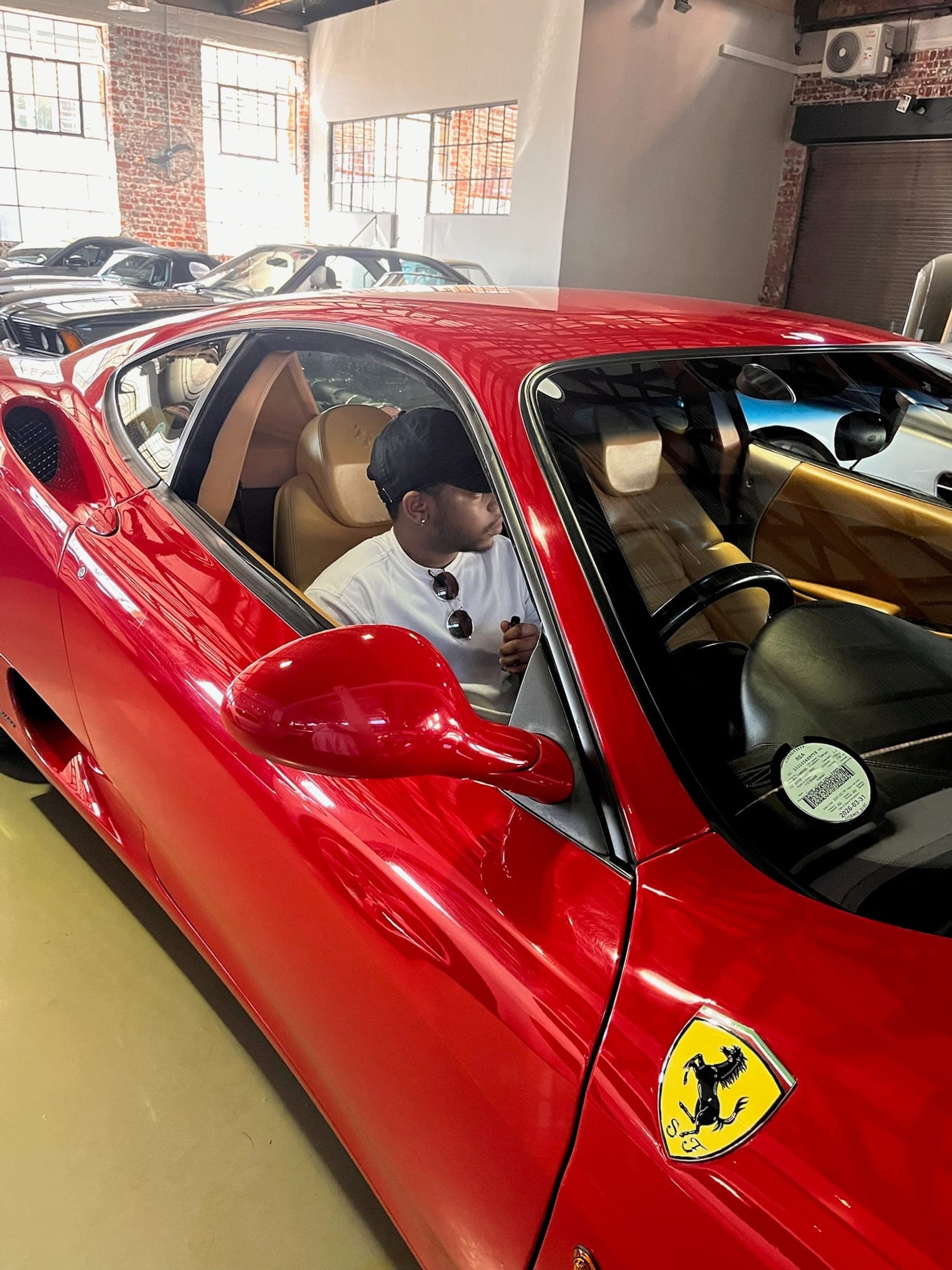 Katleho Mohlomi in the driver's seat of a Ferrari on a showroom floor